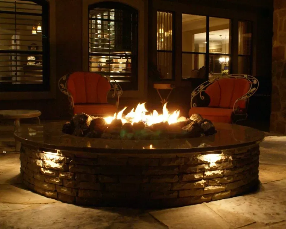 A fire pit in the middle of a patio at night.