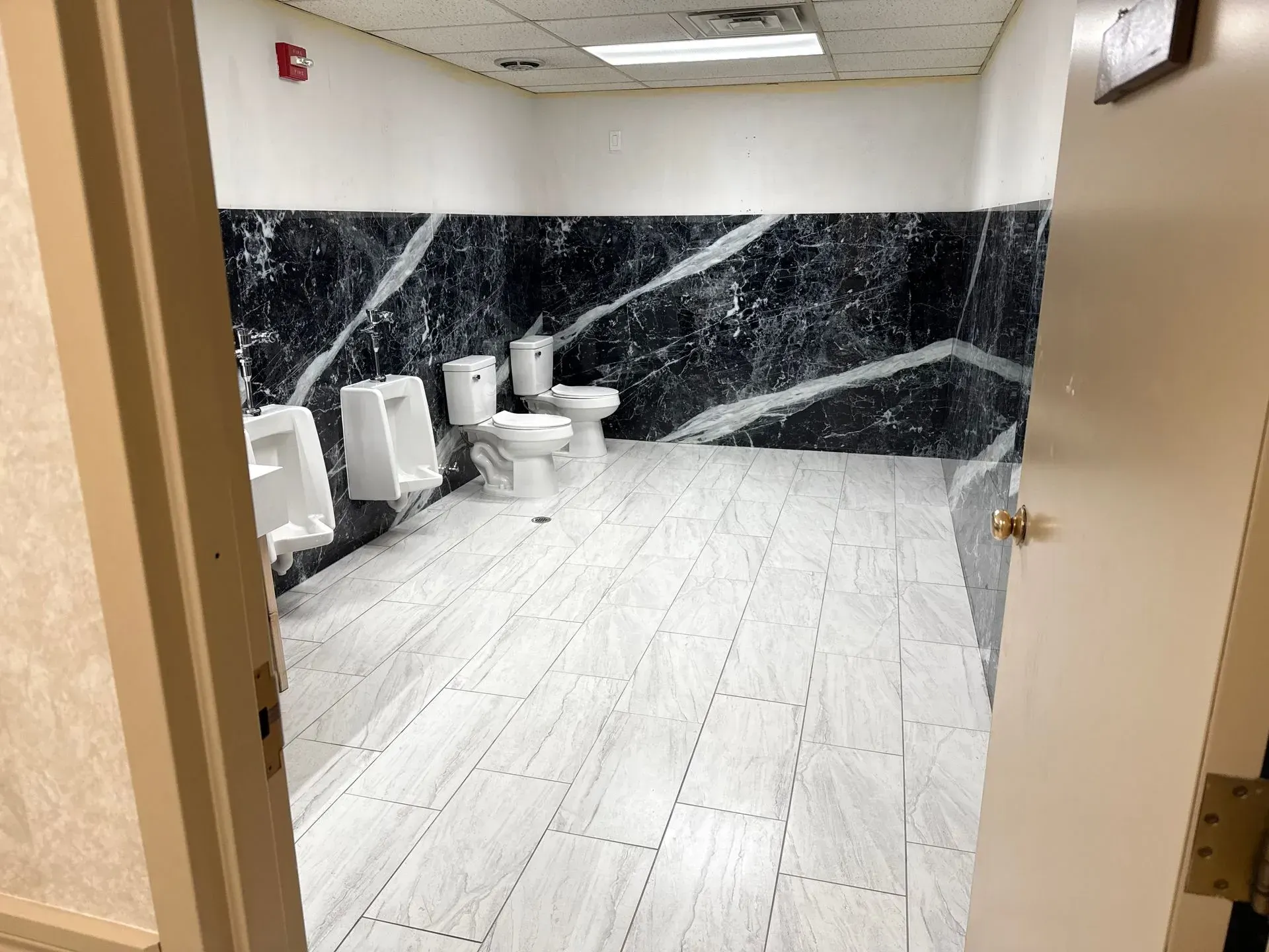 A bathroom with two toilets and urinals in it.