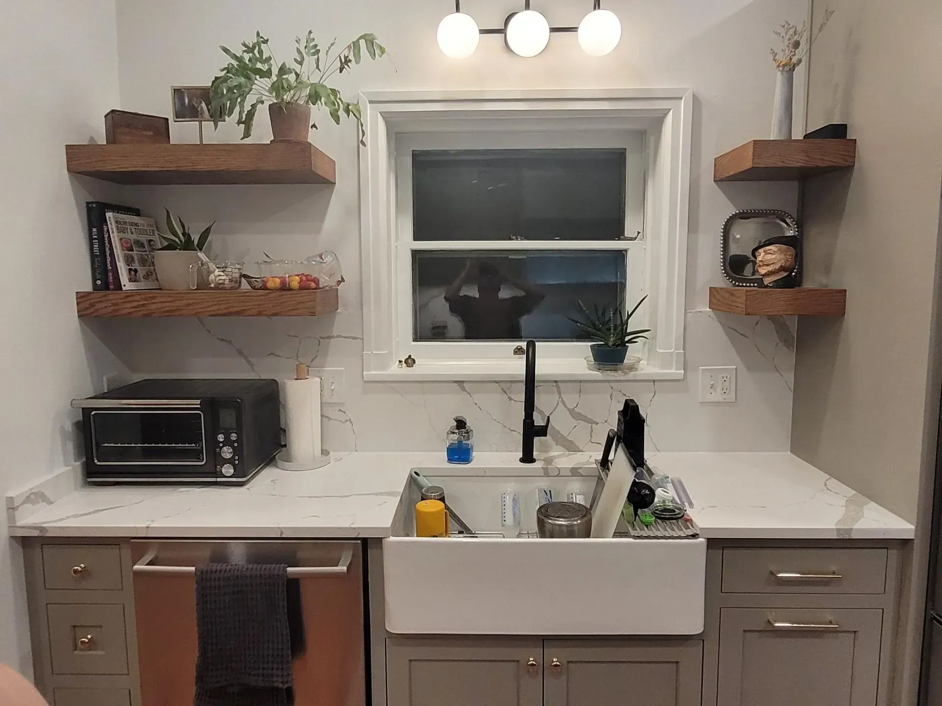 A kitchen with a sink, microwave, and shelves.