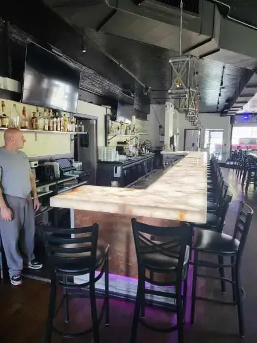 A man is standing in front of a long bar in a restaurant.