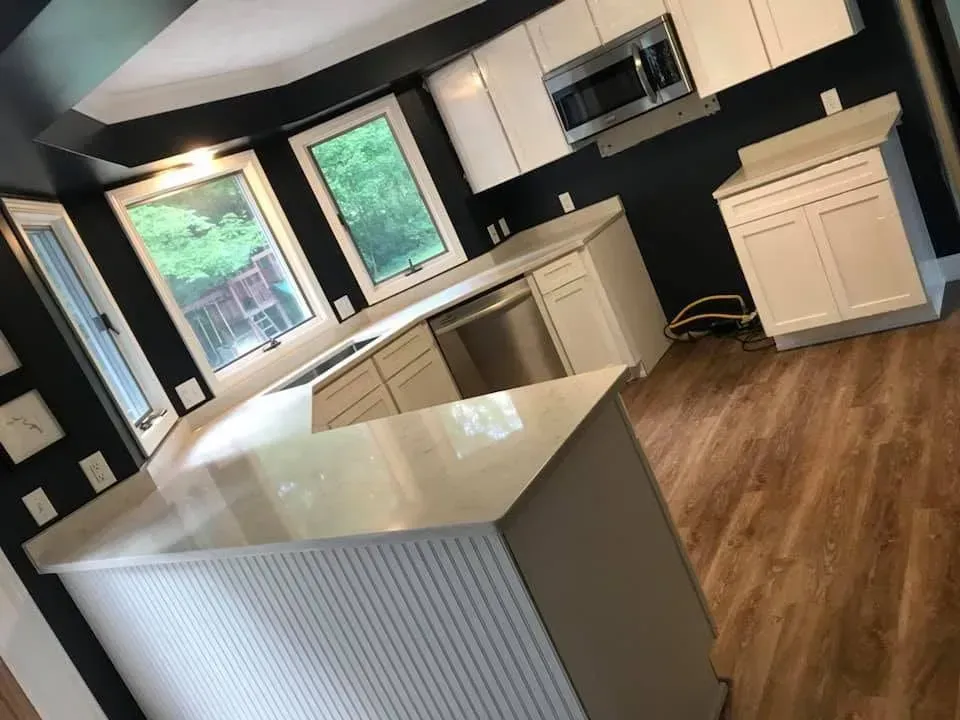 A kitchen with black walls and white cabinets and a large island in the middle.