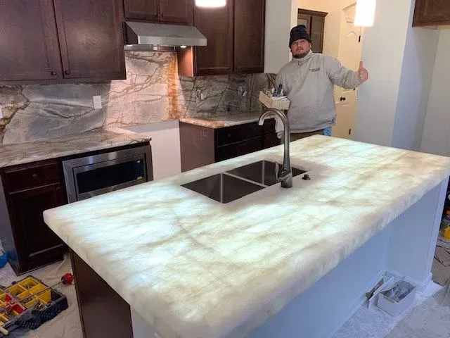 A man is standing in a kitchen next to a sink.