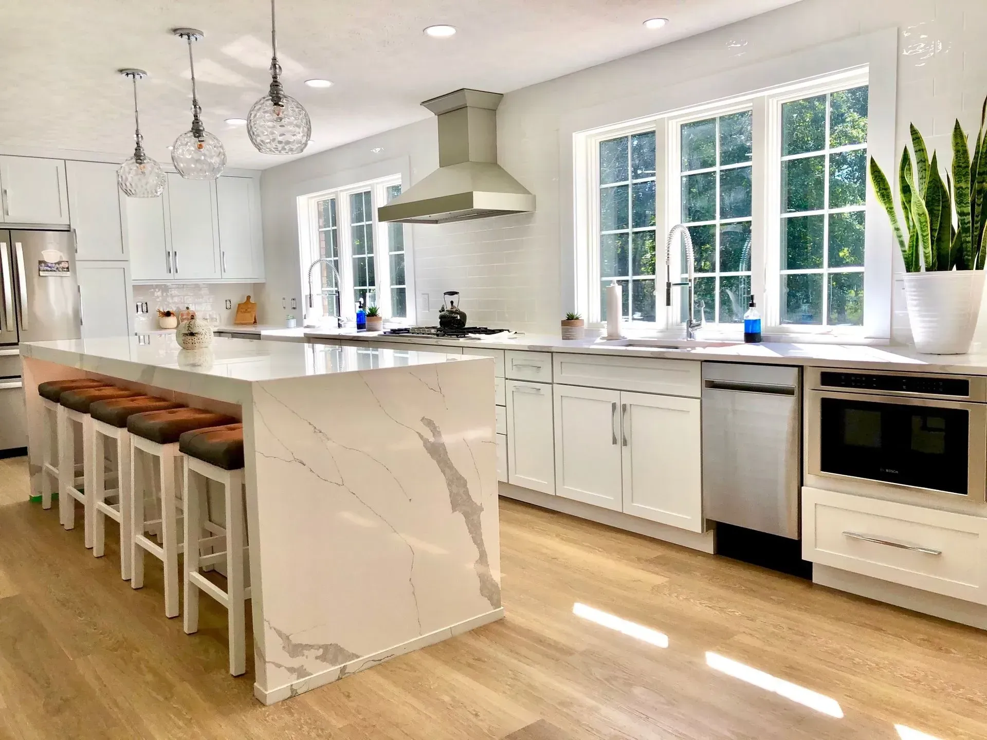 A kitchen with white cabinets, stainless steel appliances, and a large island.