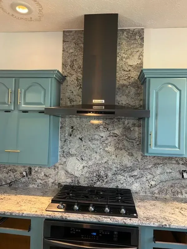 A kitchen with blue cabinets and a stove top oven.