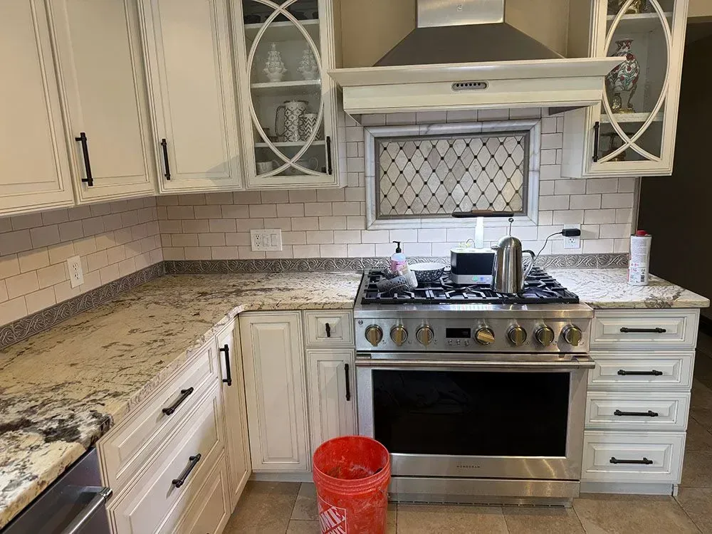 A kitchen with stainless steel appliances and white cabinets.