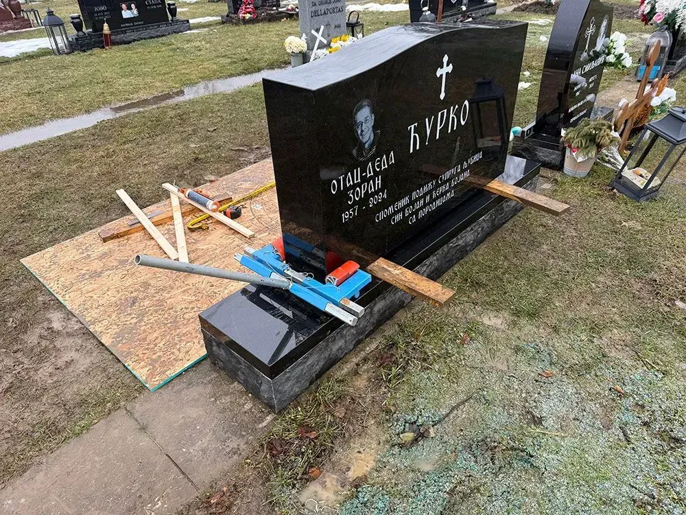 A black gravestone with a cross on it.