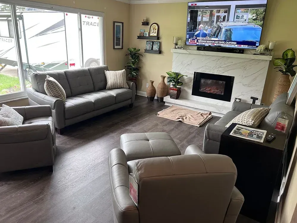 A living room with a couch, chairs, television, and fireplace.