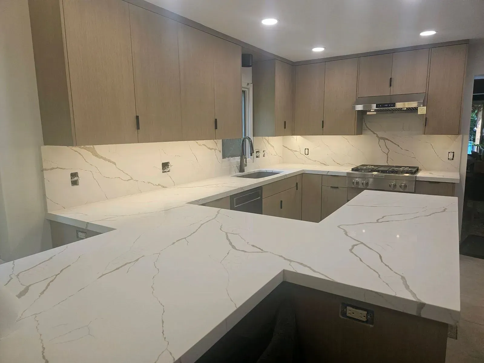 A kitchen with white counter tops and wooden cabinets.