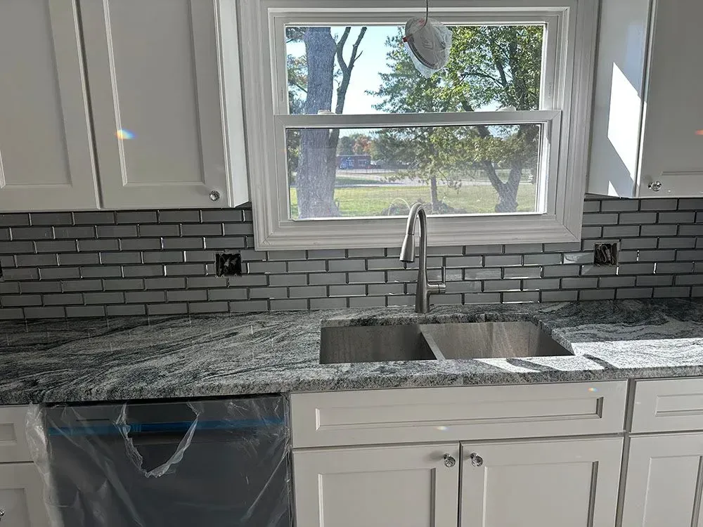 A kitchen with a sink, dishwasher, and window.