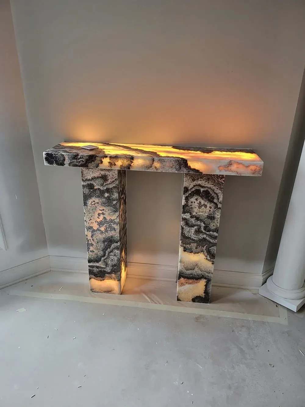 A marble table with a light on it is sitting on the floor next to a wall.