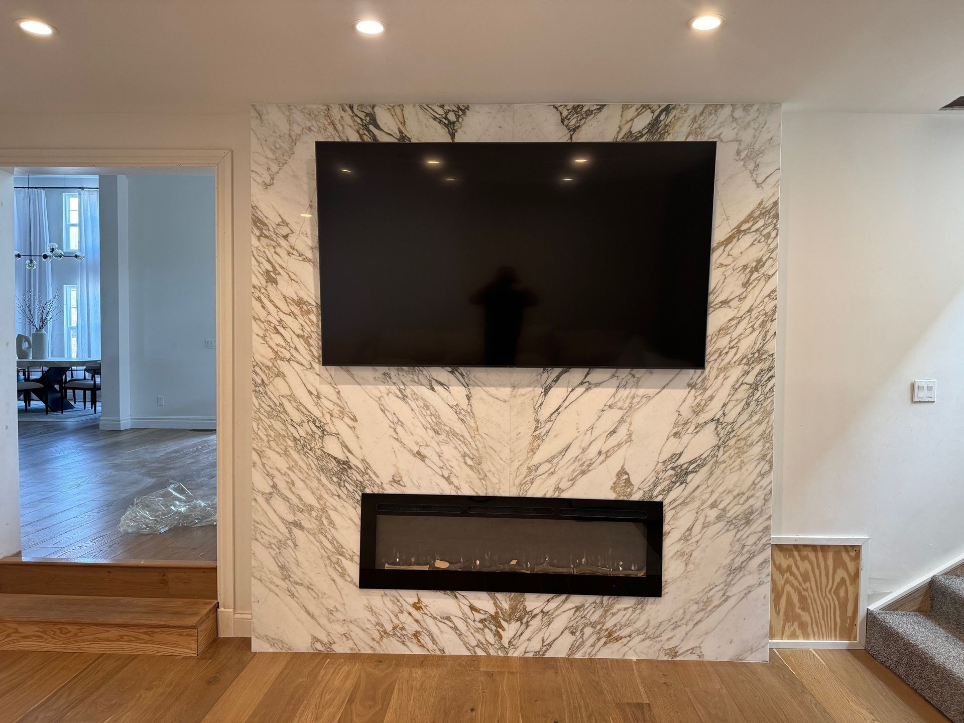 A living room with a fireplace and a flat screen tv on the wall.
