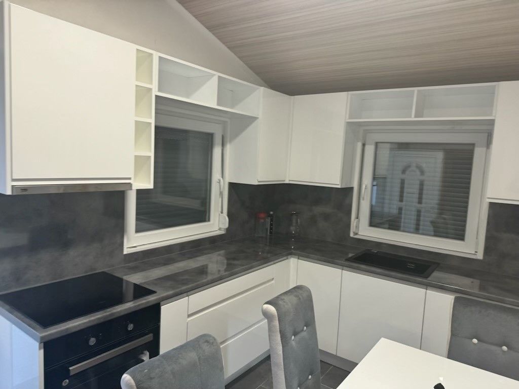A kitchen with white cabinets, a black stove top oven, a table, and chairs.