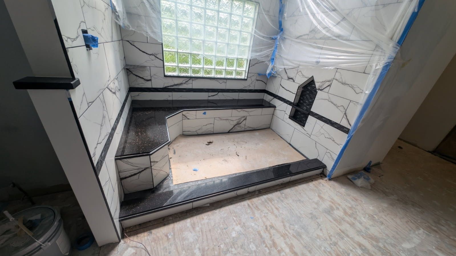 A bathroom under construction with marble tiles and a window.
