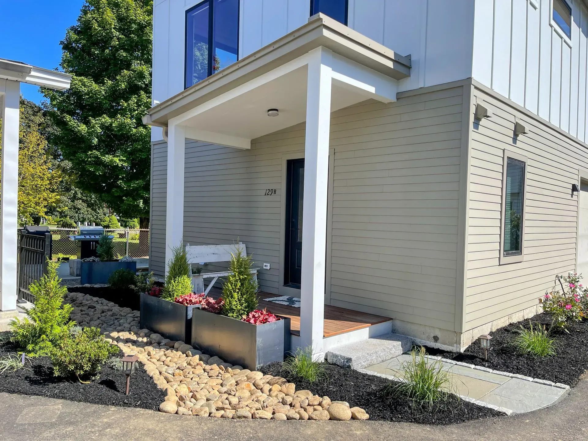Modern home exterior with covered entrance, planters, and landscaping.