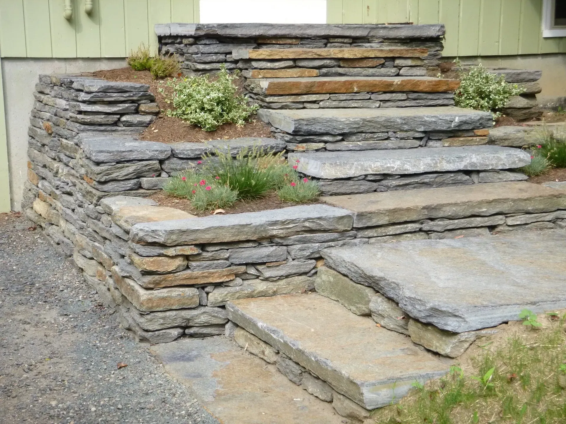 Stone steps with built-in planters, ascending a green building.