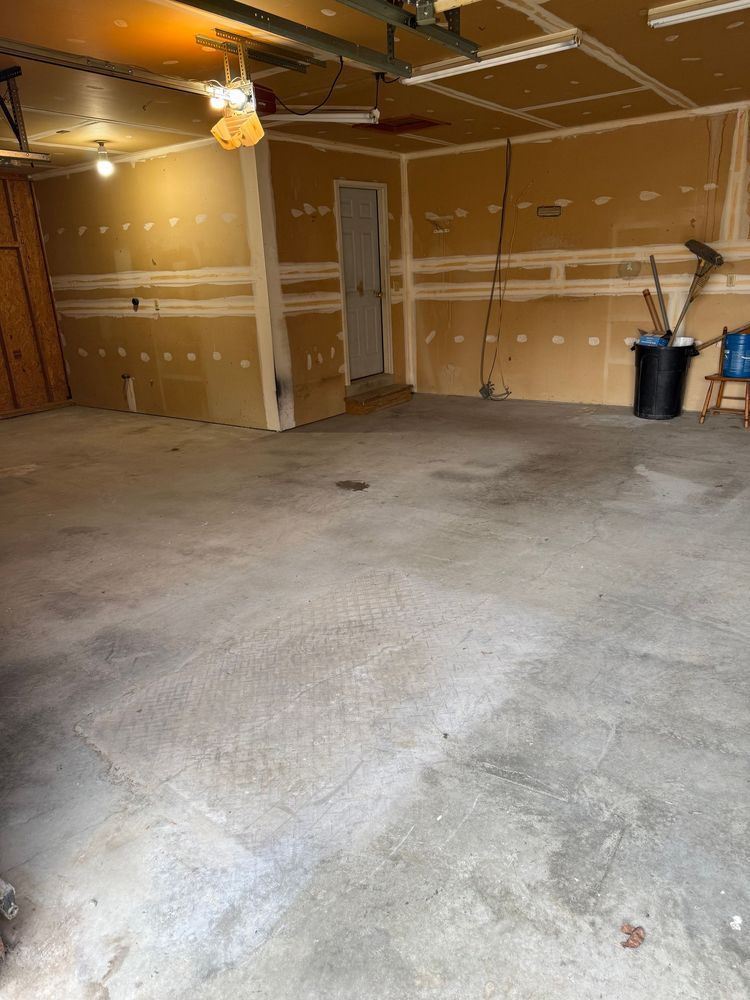 Empty garage with concrete floor, unfinished walls, and a closed door.
