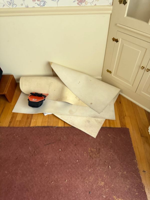 Construction materials on floor: rolled fabric, paper, and cone-shaped piece, next to a cabinet.