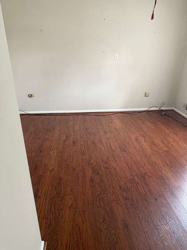 Empty room with brown hardwood floors and beige walls.