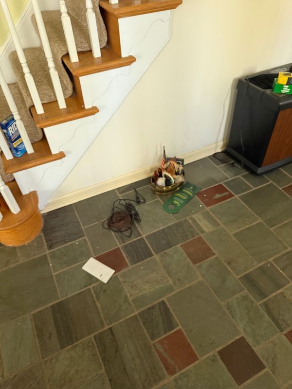 Slate tile floor with a staircase, basket, and clutter.