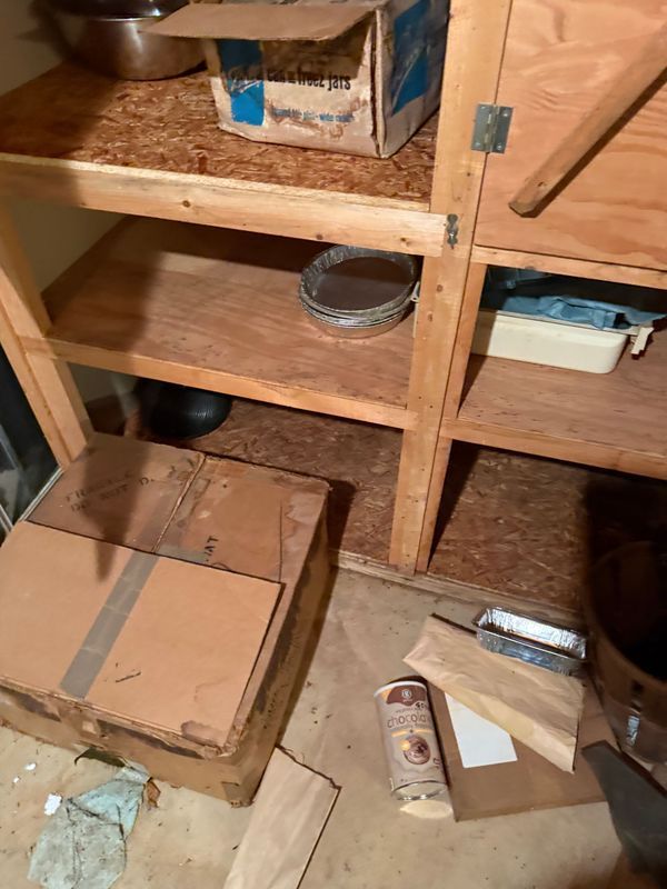 Wooden shelving unit with boxes and containers inside and on the floor.