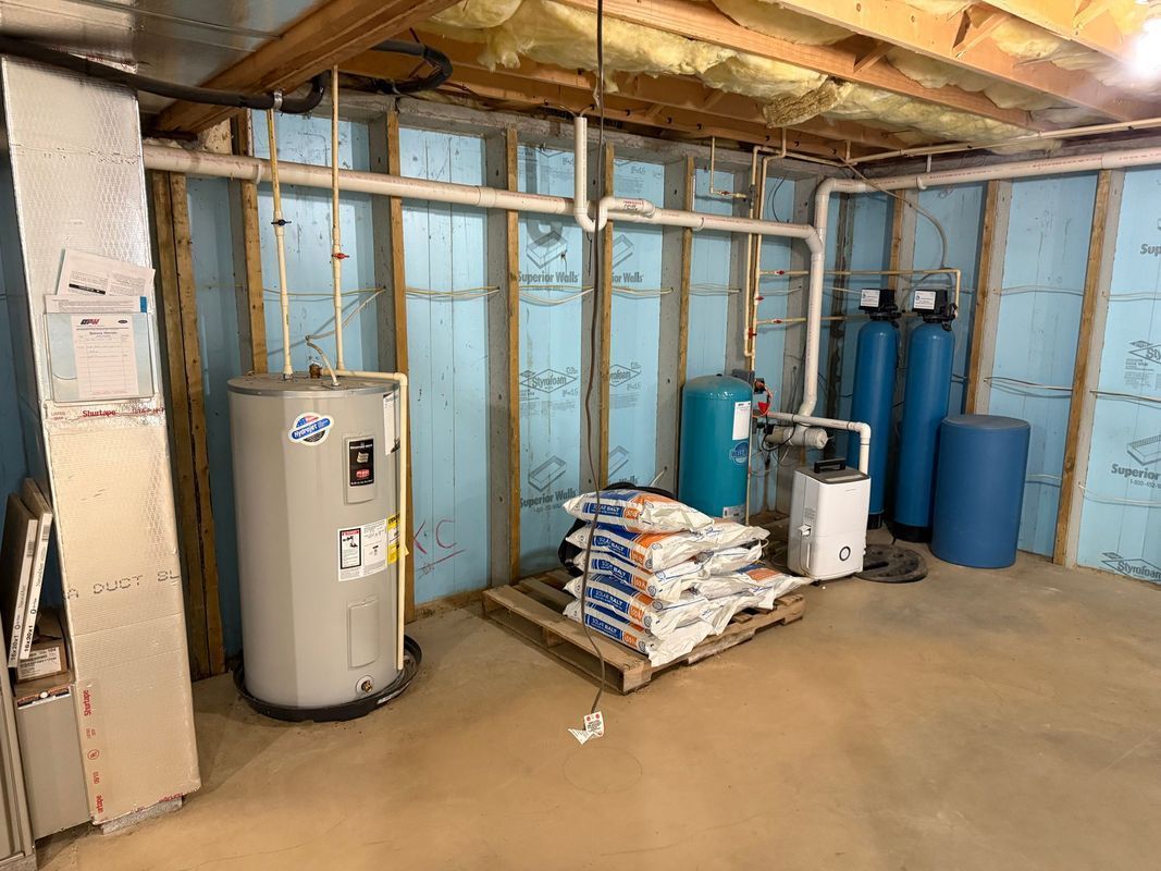 Basement with water heater, water treatment system, and bags of salt. Blue insulated walls.