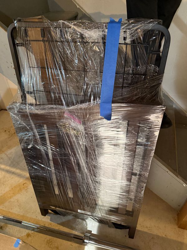 Wrapped furniture, brown and black, taped with blue tape, sits on stairs.