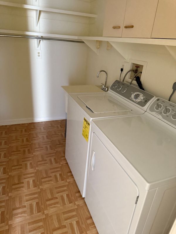 Laundry room with white washer and dryer, sink, cabinets, and brown patterned floor.