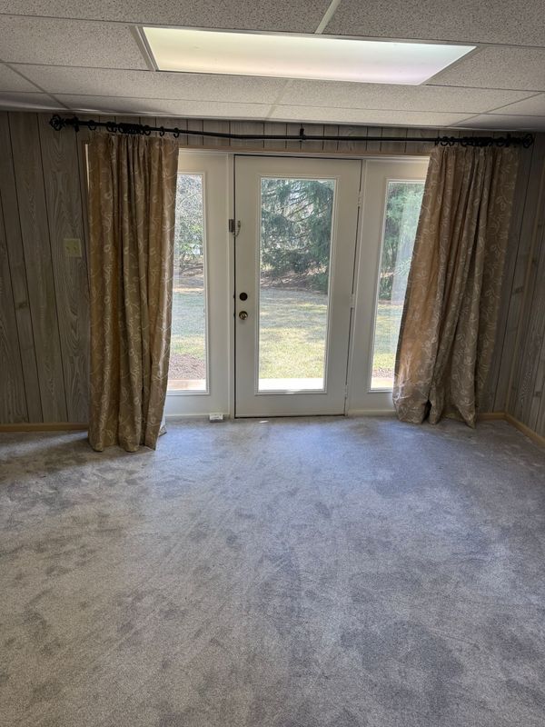 Room with carpet, glass doors, and curtains. Light from a ceiling panel illuminates the interior.