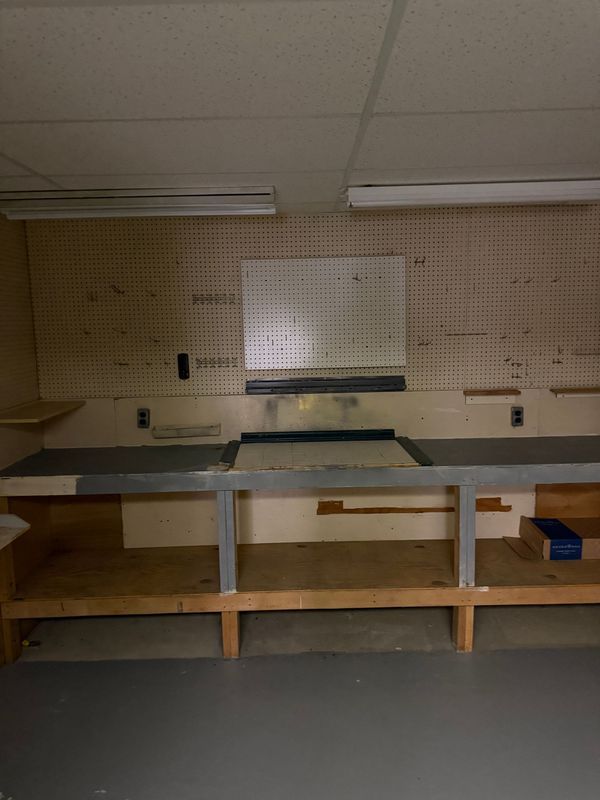 Workshop with pegboard, workbench, and shelving. Gray floor, beige walls and ceiling.