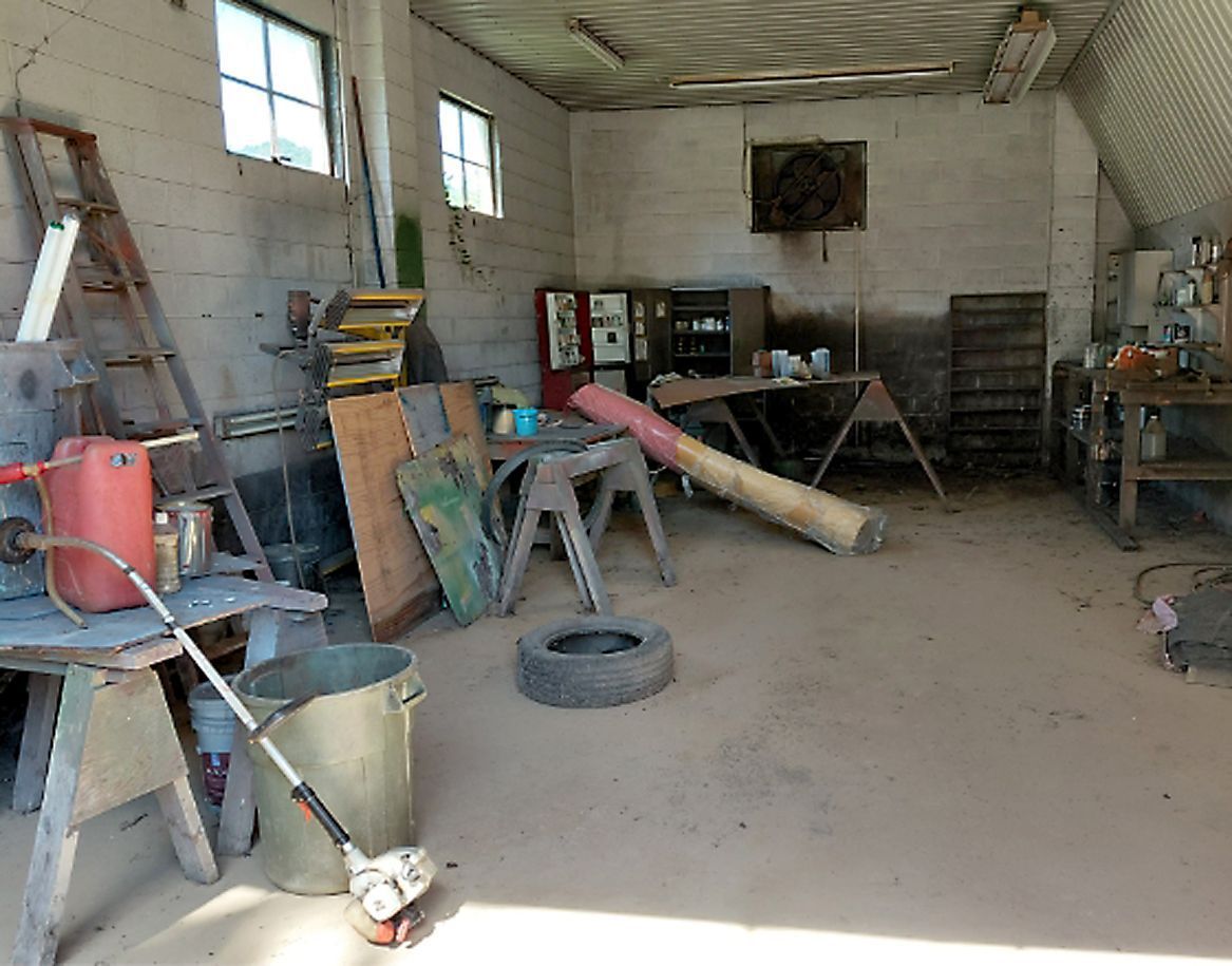 Cluttered workshop interior with tools, workbenches, and various objects.