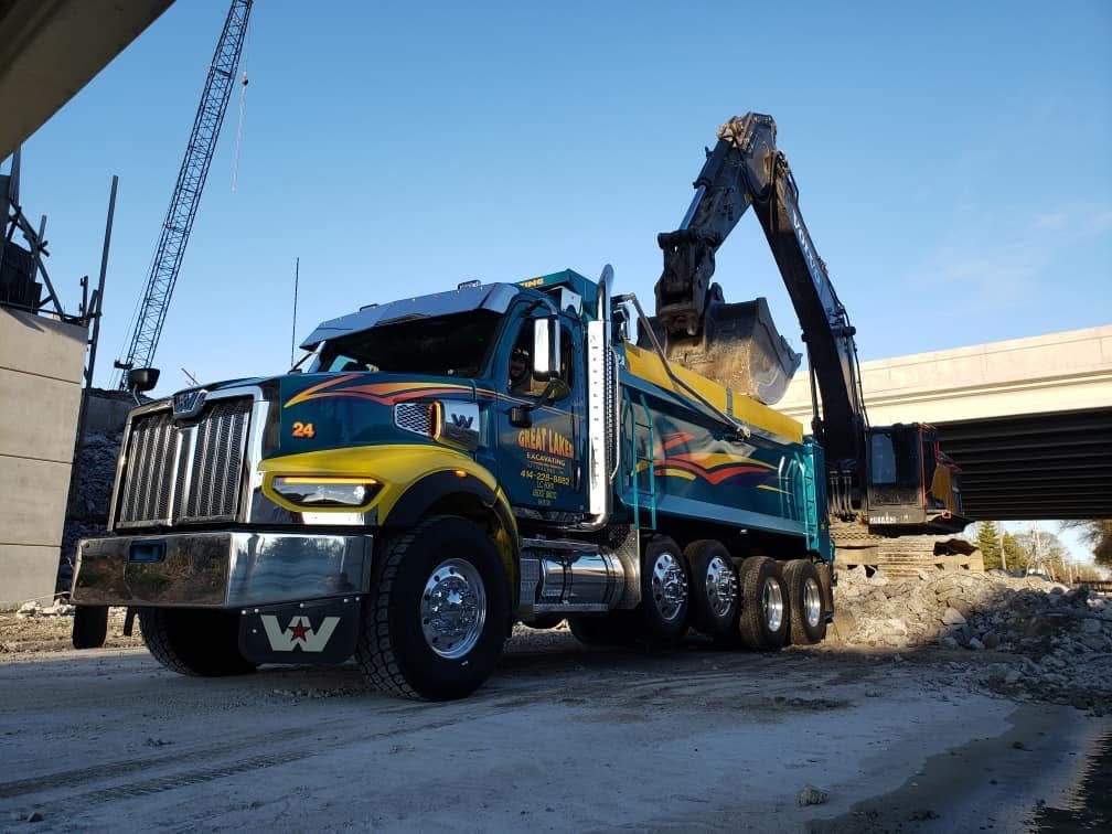 Dump truck being loaded with debris by an excavator at a construction site.