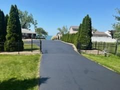 a driveway leading to a house with a lake in the background.