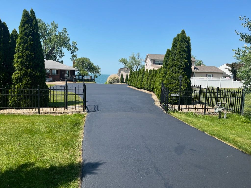 a driveway leading to a house with a lake in the background.