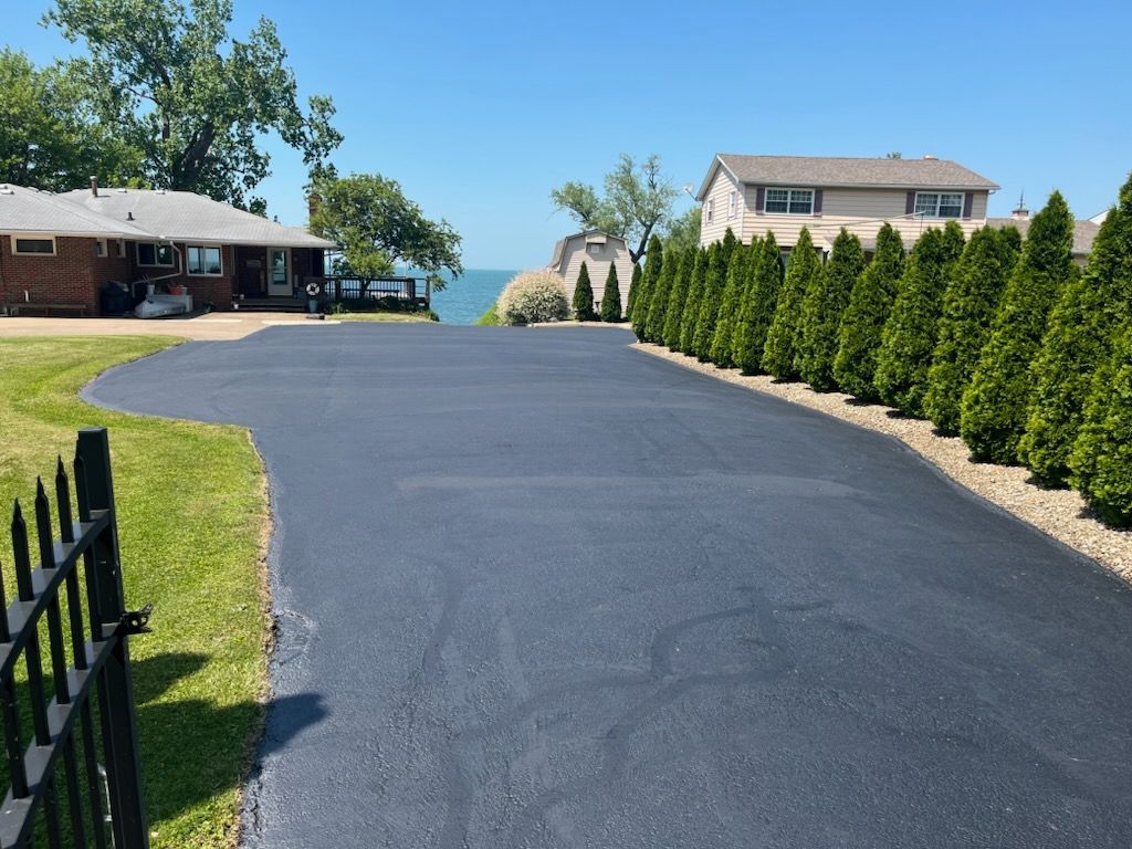 a driveway leading to a house surrounded by trees and grass.