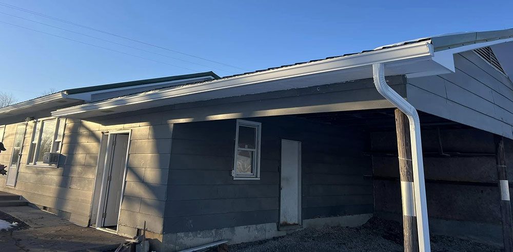 A house under construction with a white gutter and a blue sky in the background.