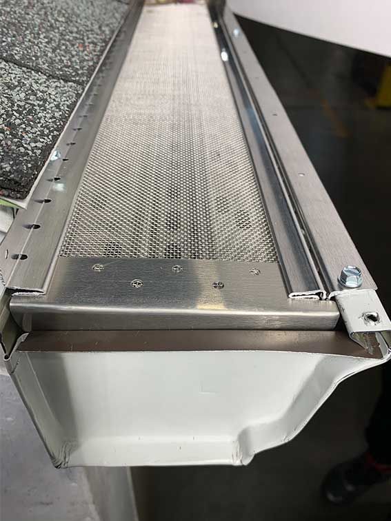 A close up of a gutter with a mesh screen attached to it.