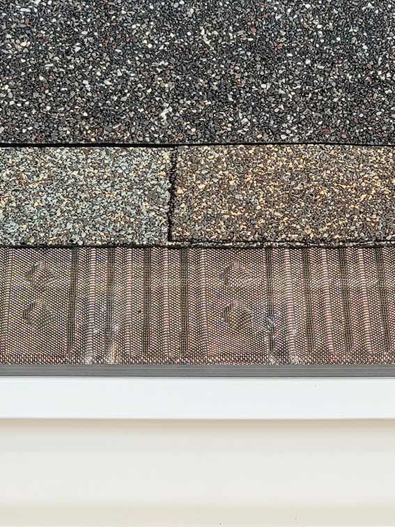 A close up of a roof shingle on a wooden floor.