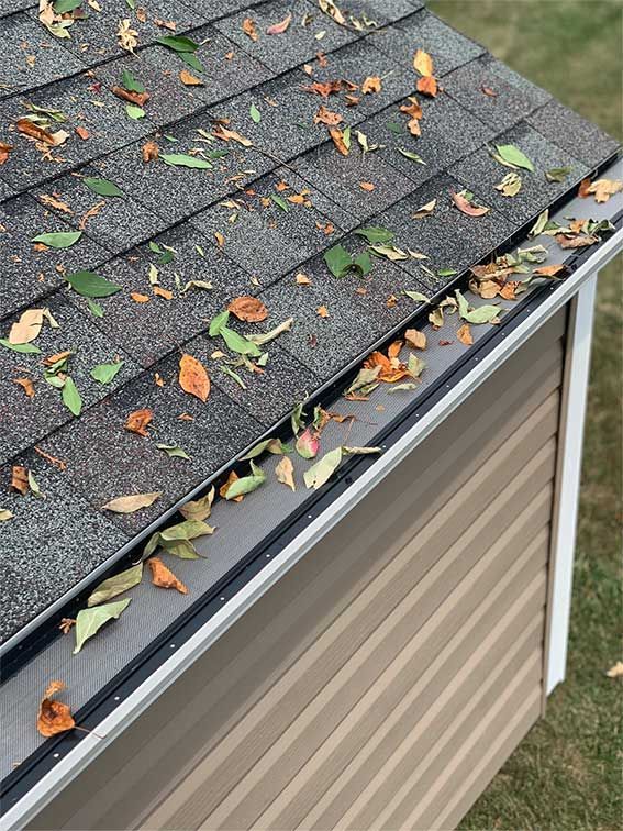 A gutter filled with leaves on the roof of a house.