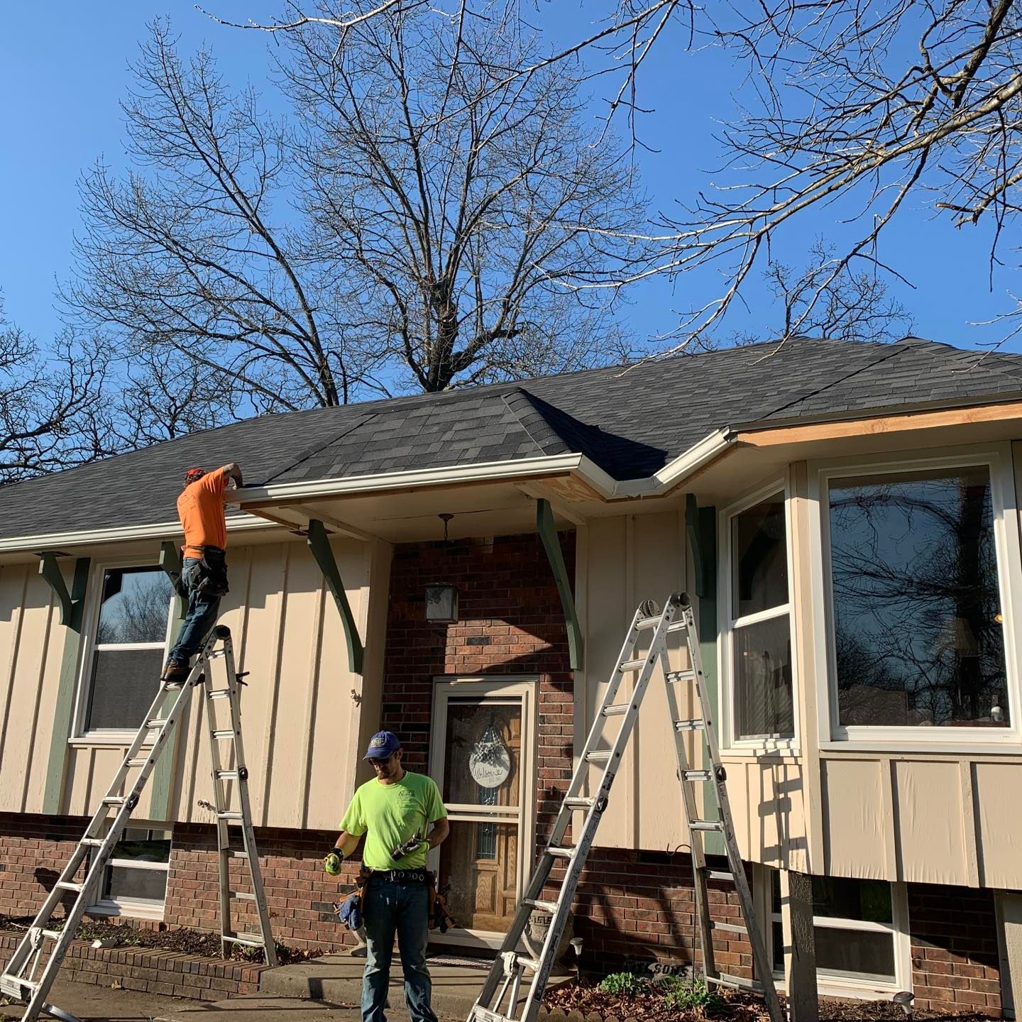 Two men are working on the roof of a house.