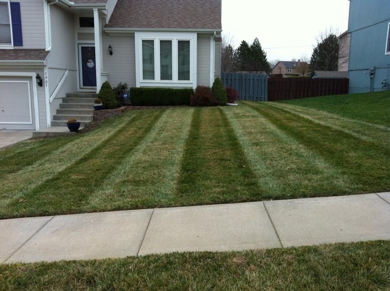 A residential suburban home with a freshly mown lawn featuring distinct, symmetrical striping patterns.