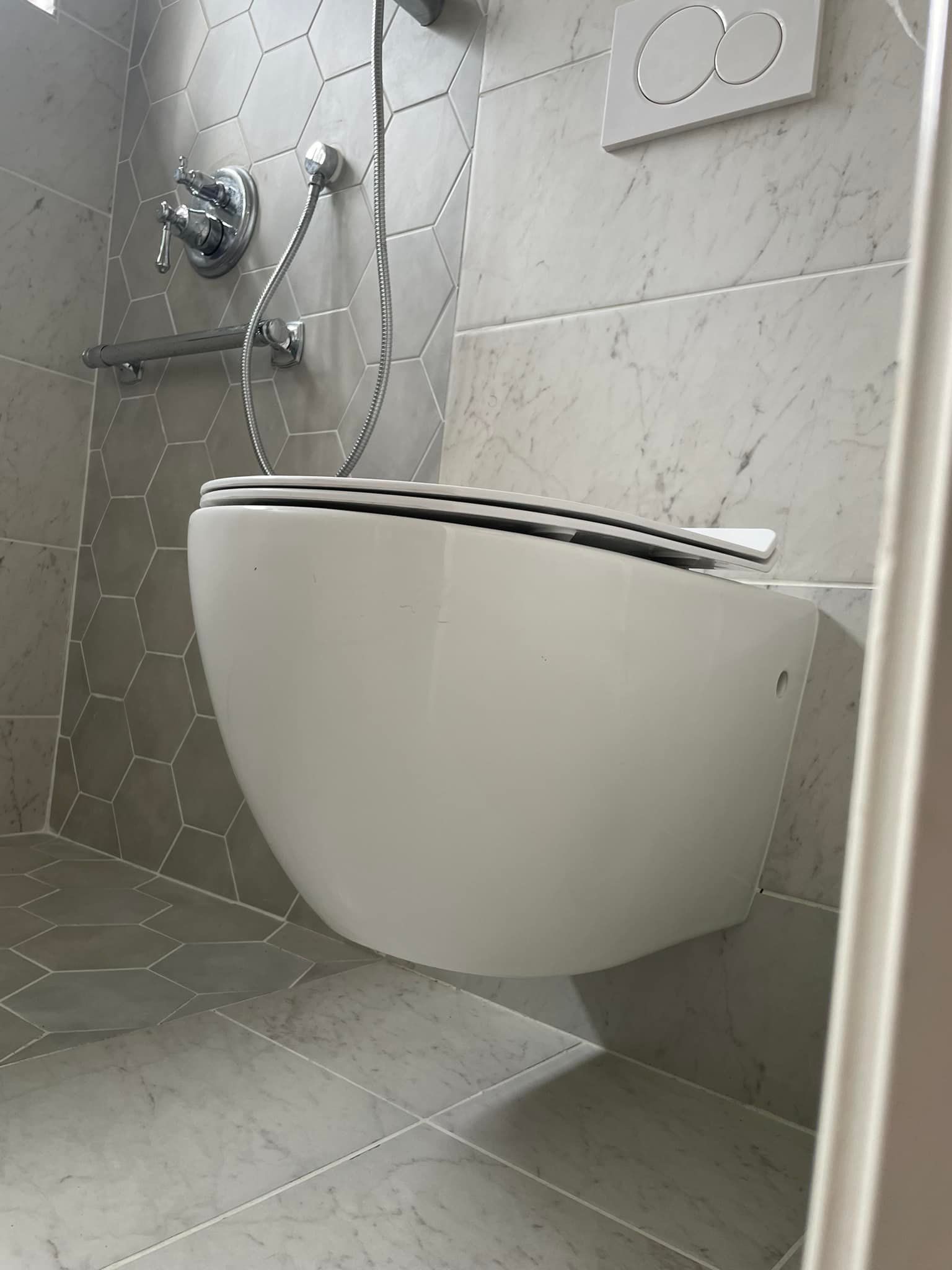 A white toilet is hanging from the wall in a bathroom.