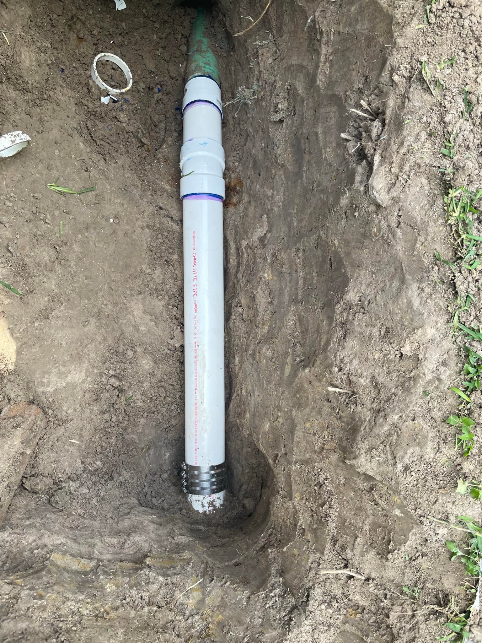 A white pipe is sitting in the dirt in a hole.