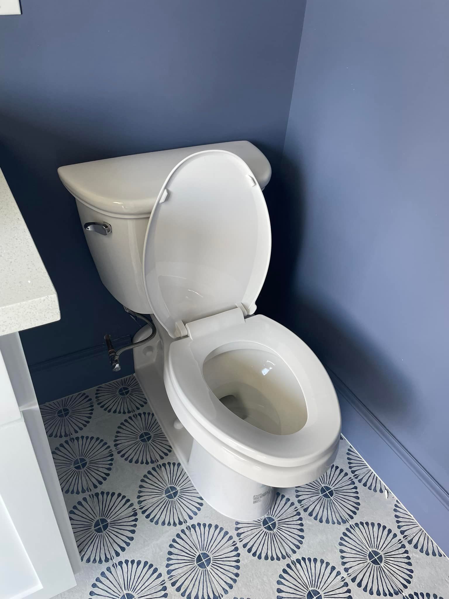 A white toilet is sitting on a tiled floor in a bathroom.