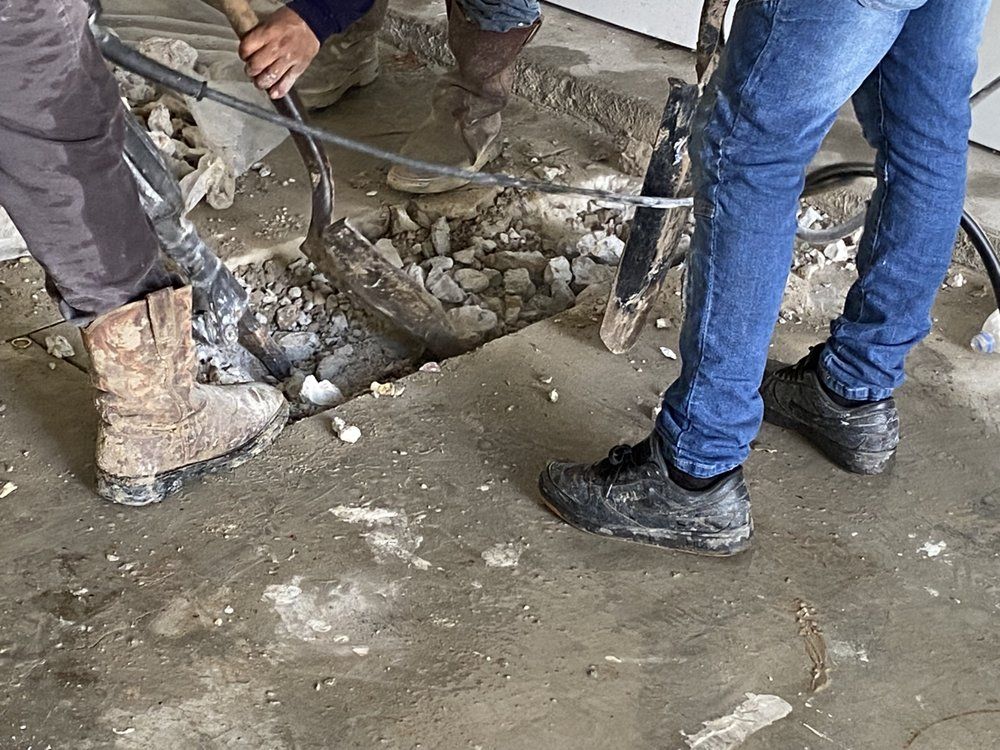 A man is using a hammer to break a hole in the floor.