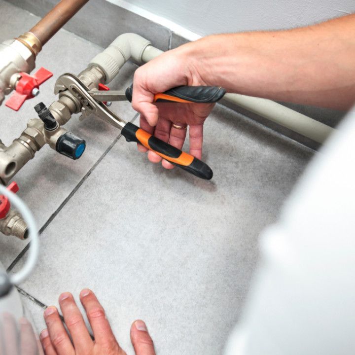 A person is working on a pipe with a wrench