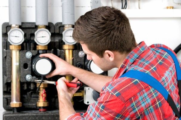 A man in a plaid shirt is working on a machine with a screwdriver.