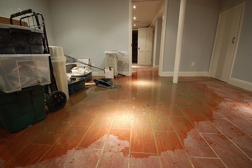 Empty hallway with glossy wooden floor, boxes and a cart on the left, doors along the walls.