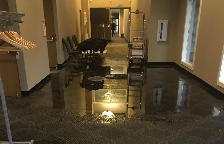 Dim hallway with a large floor flood and a chair partially submerged in water