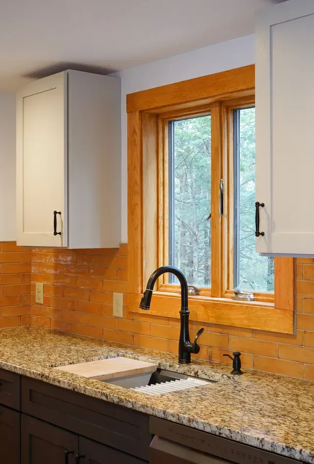 A kitchen with granite counter tops , a sink , and a window.