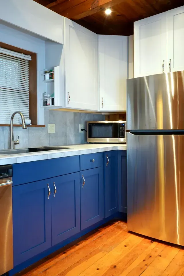 A kitchen with blue cabinets and stainless steel appliances